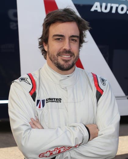 Fernando Alonso standing with folded arms in a white United Autosports racing suit